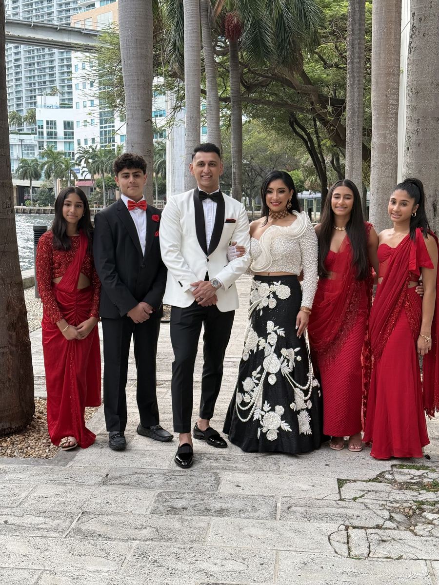Family styled in coordinated red and black formal wedding attire