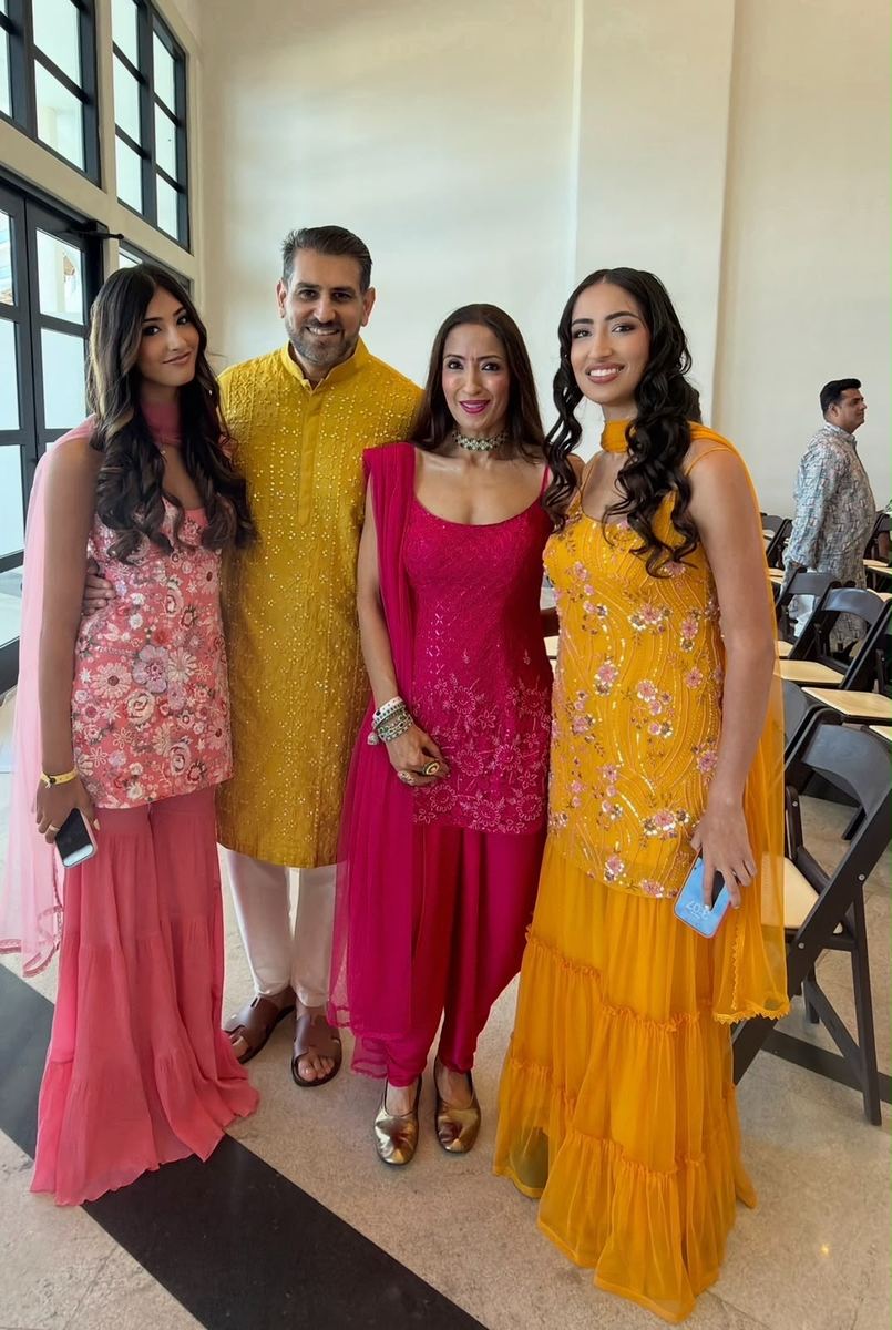 Family styled in coral, gold, and pink Indian wedding attire